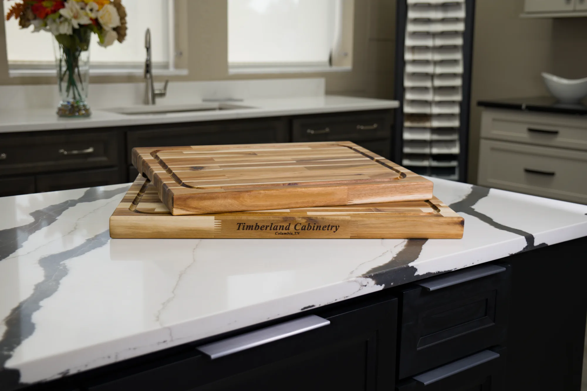 Two Timberland Cabinetry butcher block cutting boards stacked on a marble kitchen island