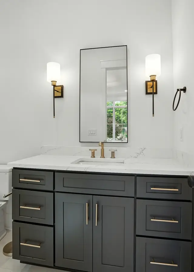 Charcoal vanity with a quartz top and brass sconces