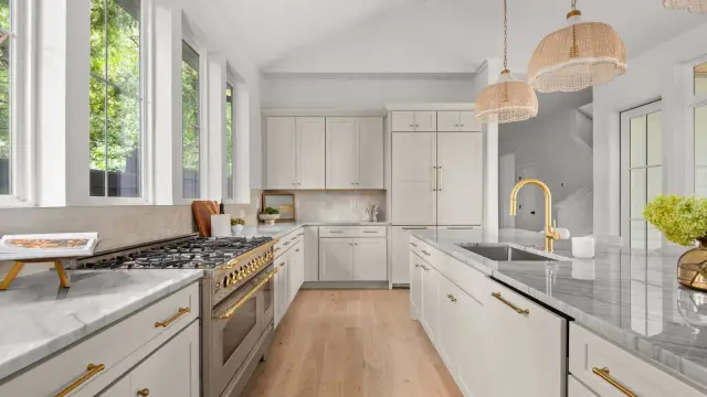 Perimeter cabinetry with brass fixtures and marble