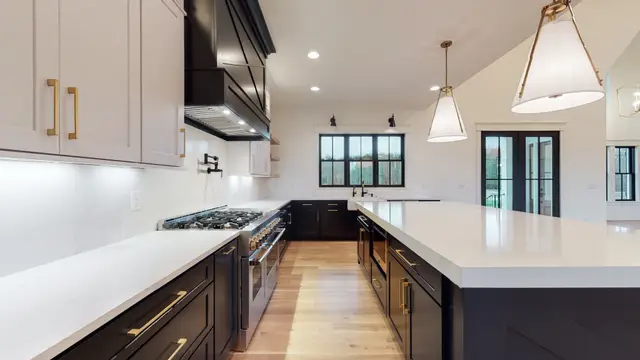 Black base cabinets under a Timberland White perimeter and dark hood