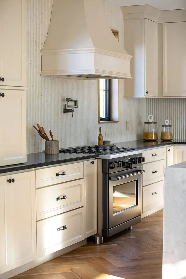 Oyster full overlay cabinetry with a plaster hood and fluted tile